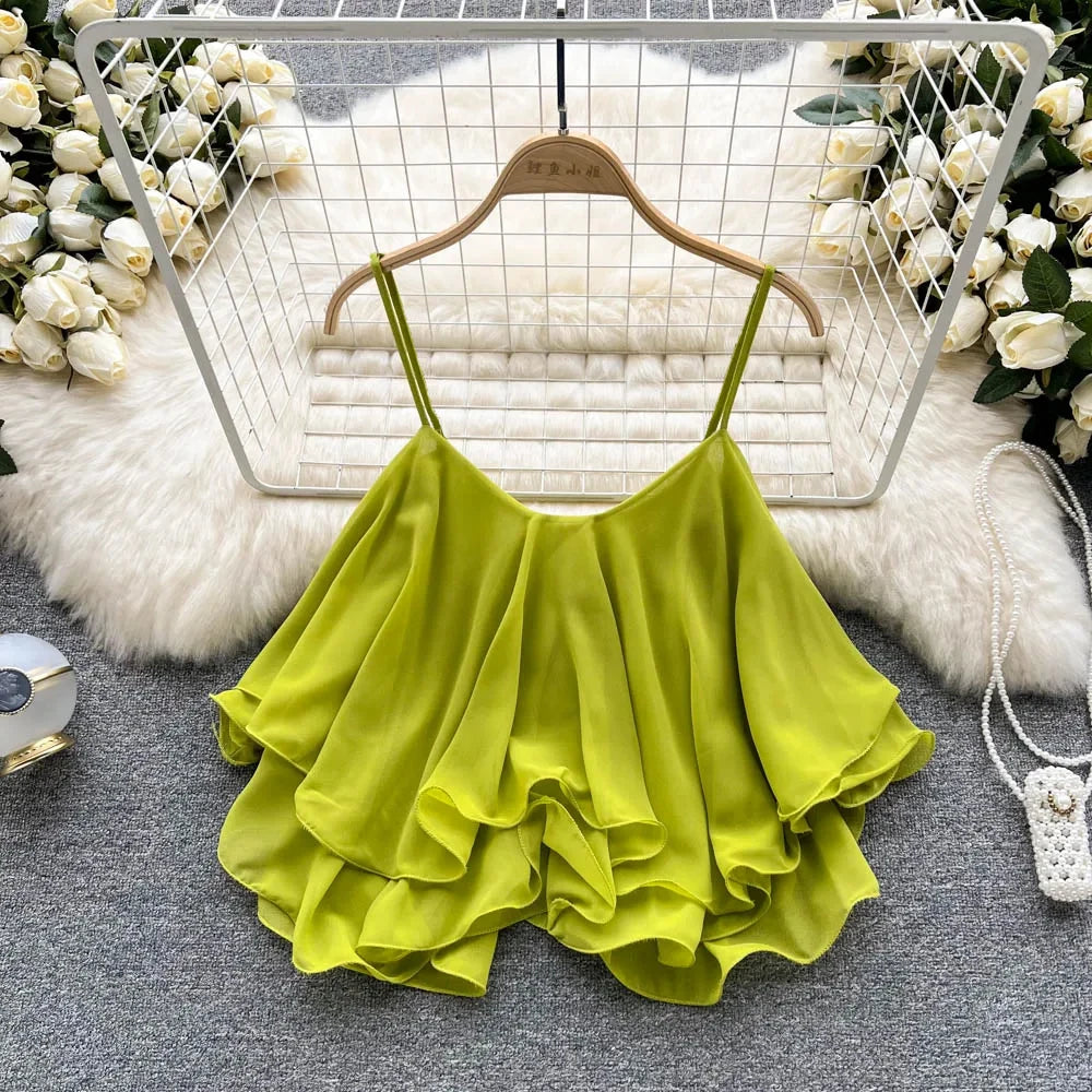 Green ruffled top on a hanger with floral decorations in the background
