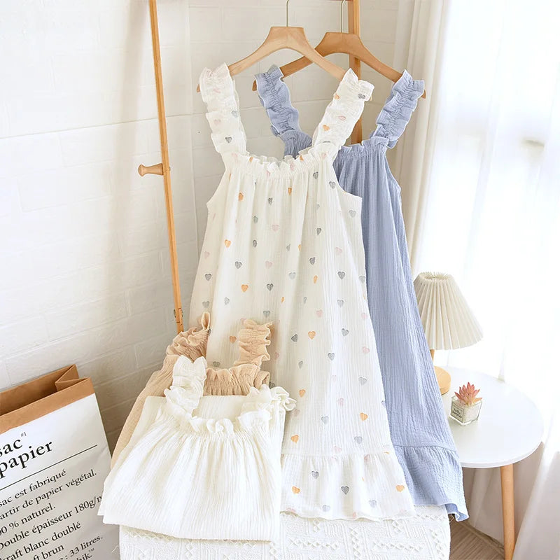 Two baby dresses, one white with heart patterns and the other blue, hanging on a rack.