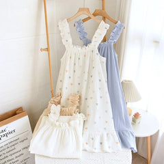 Two baby dresses, one white with heart patterns and the other blue, hanging on a rack.