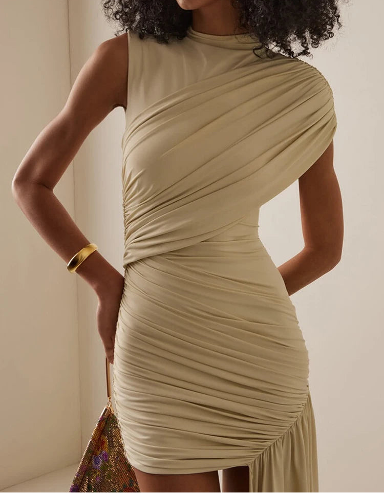 Woman wearing a beige draped dress against a neutral background