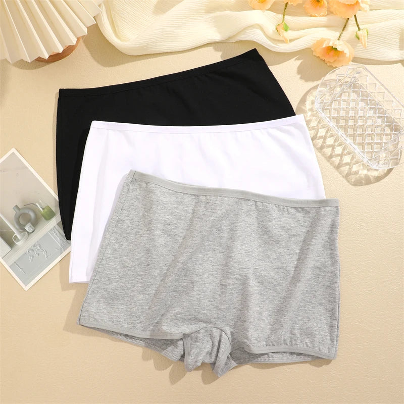 Three pairs of underwear in black, white, and gray on a beige surface.