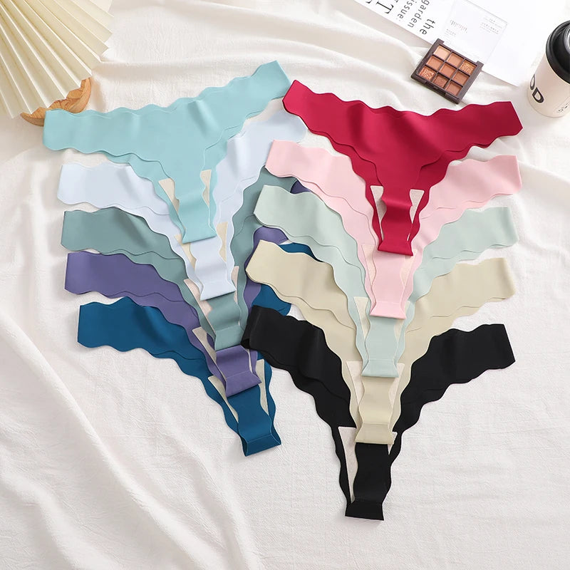 Set of colorful women's underwear on a white surface with a magazine and makeup palette in the background.