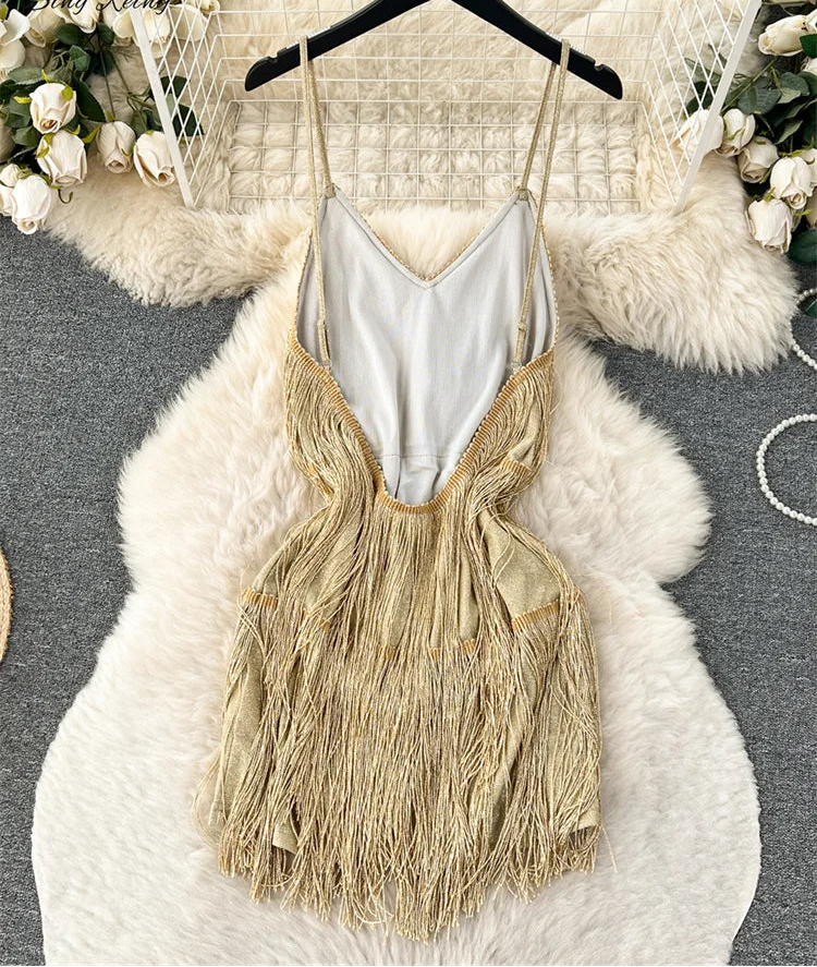 Gold fringe dress on a hanger with a white textured surface and floral decorations.
