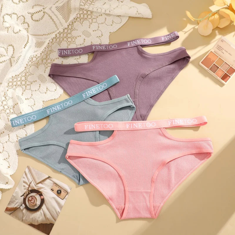 Three pairs of women's underwear in pink, blue, and purple with 'FINE TOO' branding on a decorative background.