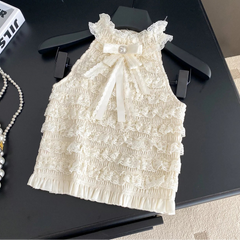 White lace dress with a bow on a black hanger against a dark surface.
