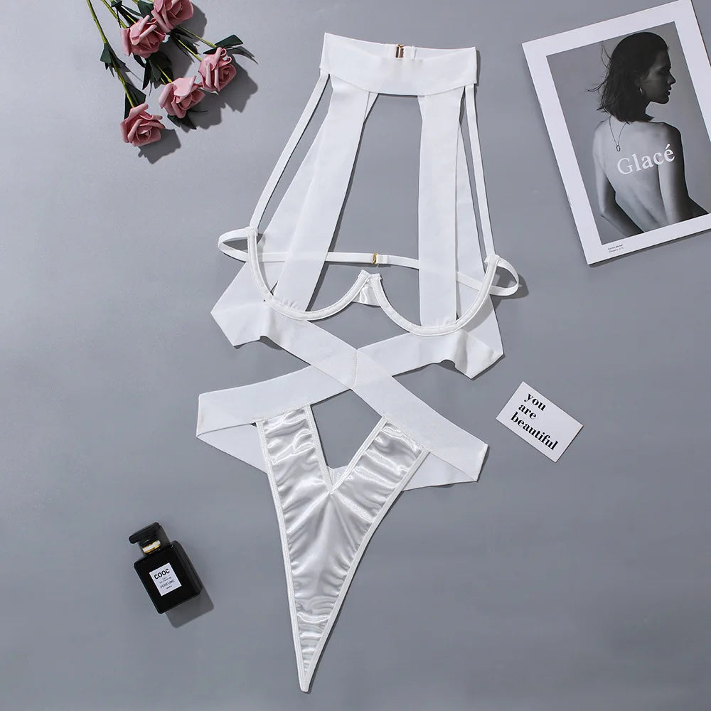 White lingerie set on a gray surface with flowers and a photo frame in the background.