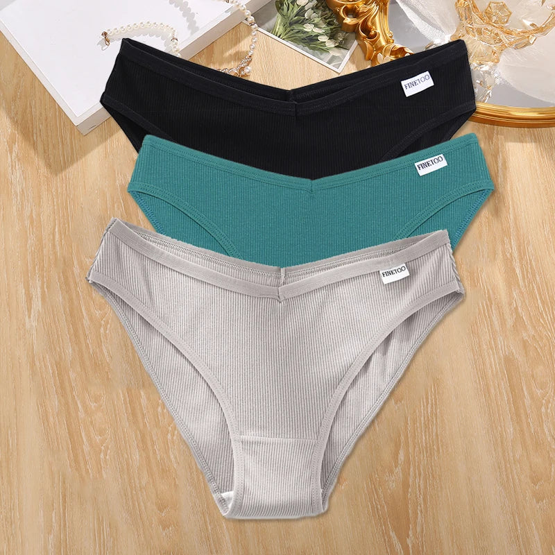 Three pairs of underwear in black, teal, and gray on a wooden surface.