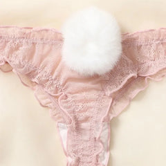 Pink lace thong with a white fluffy pom-pom on a beige background
