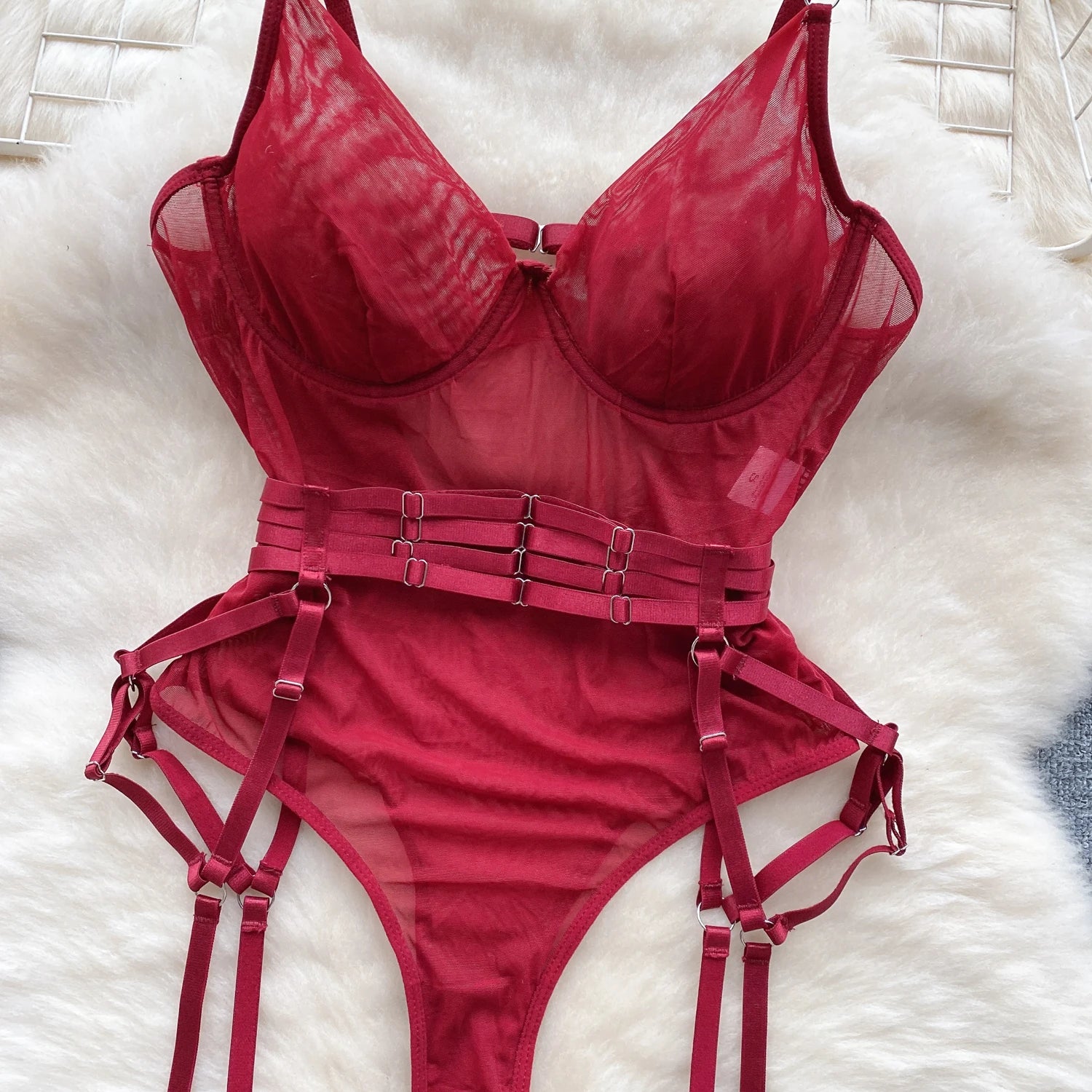 Red lingerie set with straps on a white textured surface