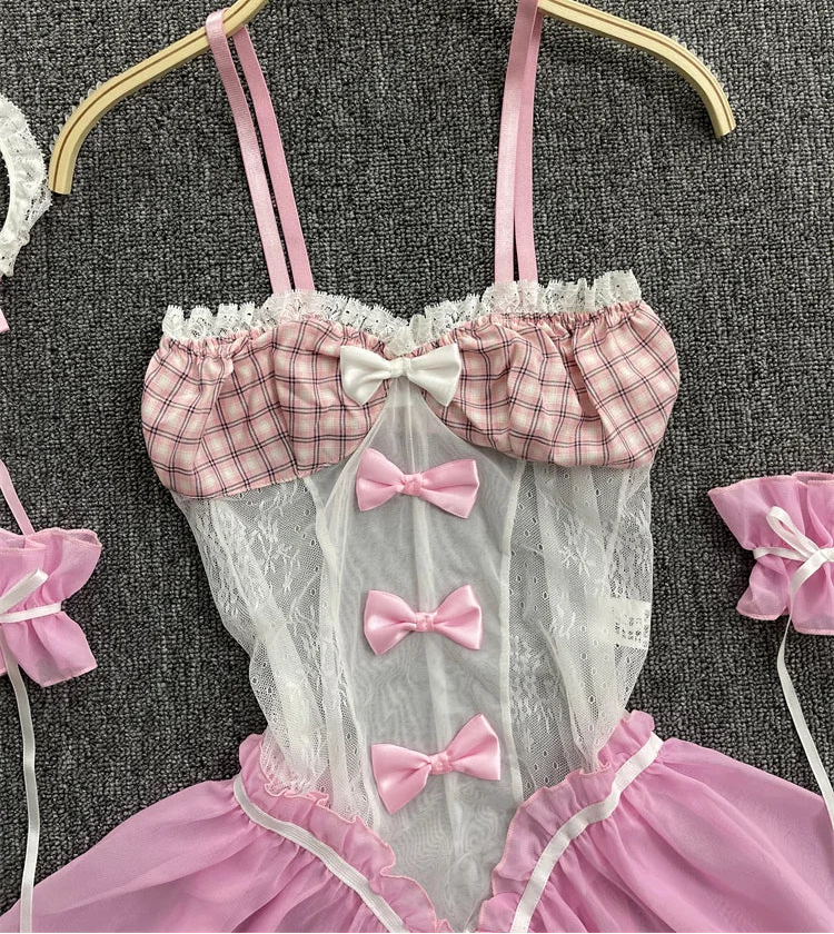 Pink and white checkered babydoll with bows on a hanger against a textured gray background.
