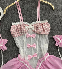 Pink and white checkered babydoll with bows on a hanger against a textured gray background.