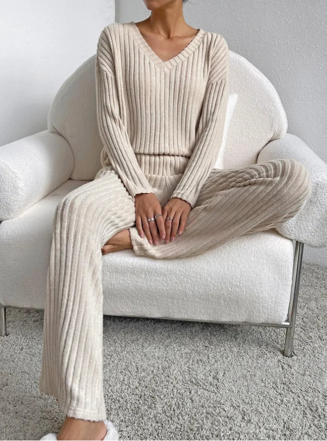 Person wearing a beige ribbed knit outfit sitting on a white chair.