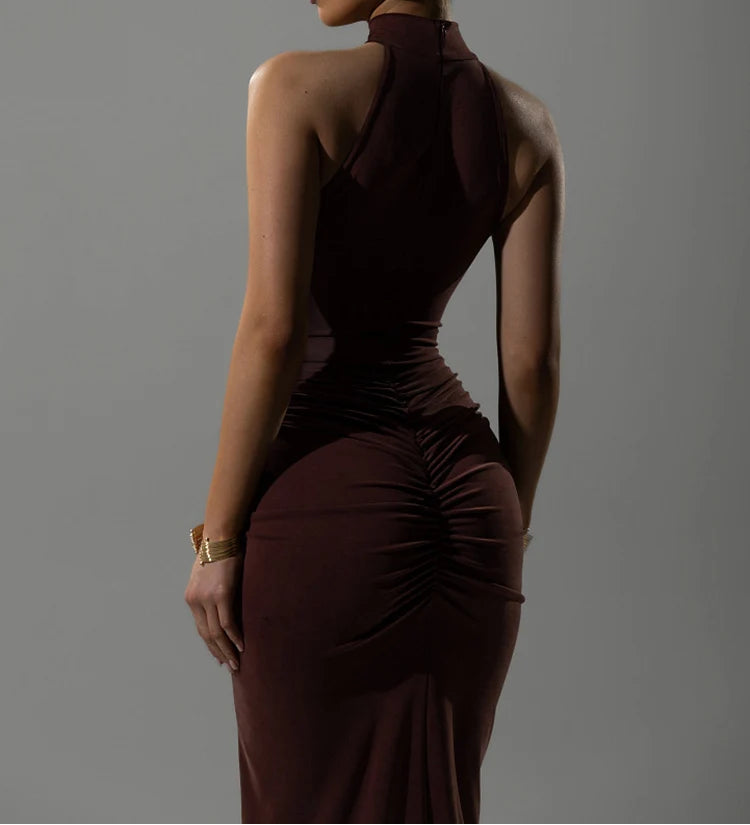 Woman wearing a dark brown halter neck dress against a gray background