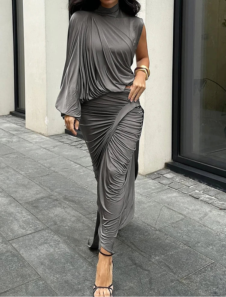 Woman wearing a gray draped dress on a city street.