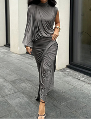 Woman wearing a gray draped dress on a city street.
