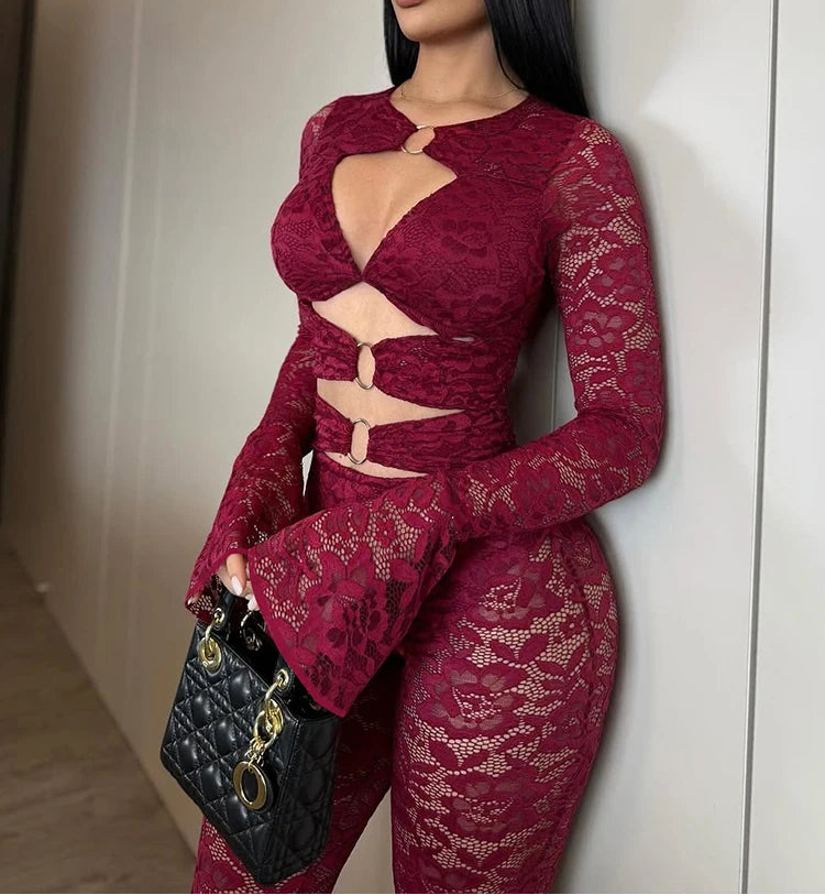 Woman wearing a burgundy lace outfit against a neutral wall.