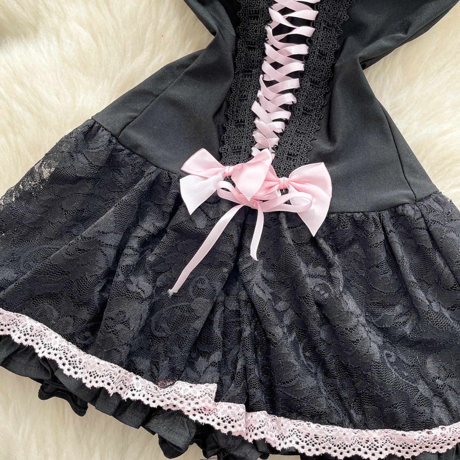 Black lace dress with pink ribbons on a light background