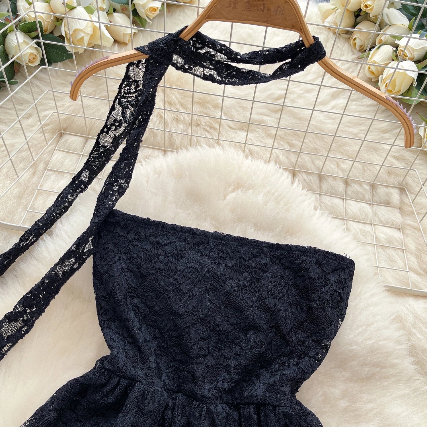 Black lace top on a hanger with a white floral background