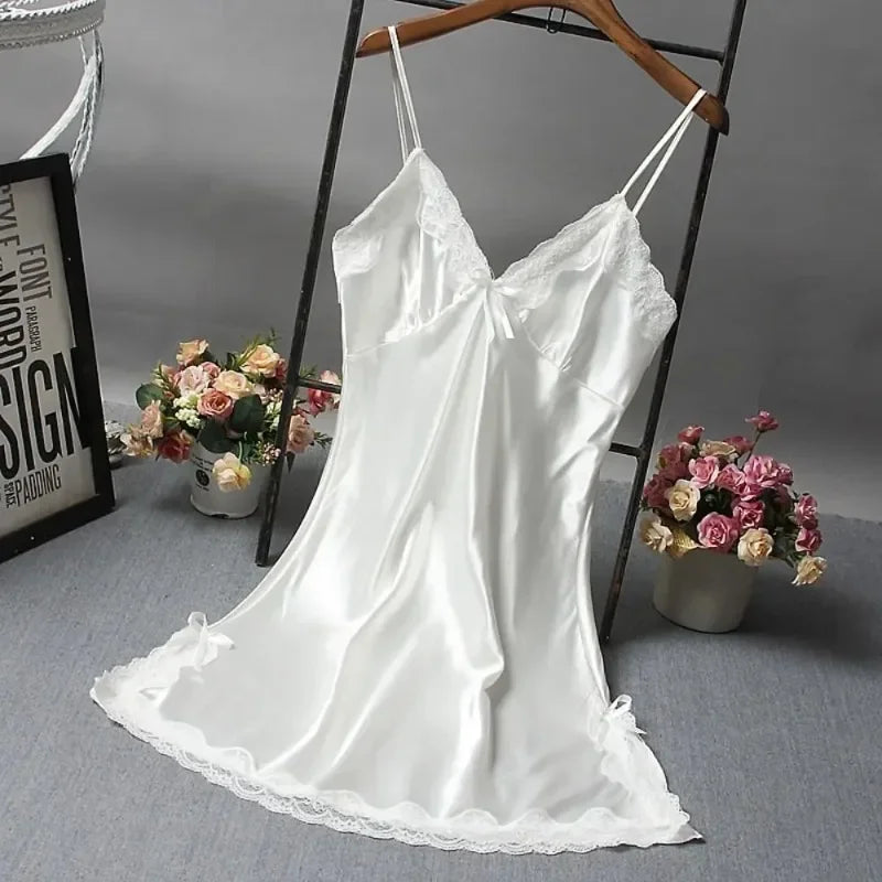 White satin slip dress on a hanger with flowers and a framed picture in the background.