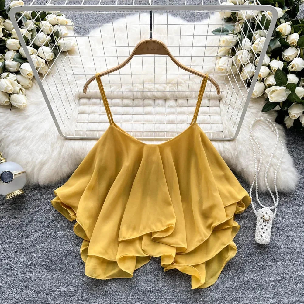 Yellow ruffled top on a hanger with decorative flowers and basket in the background