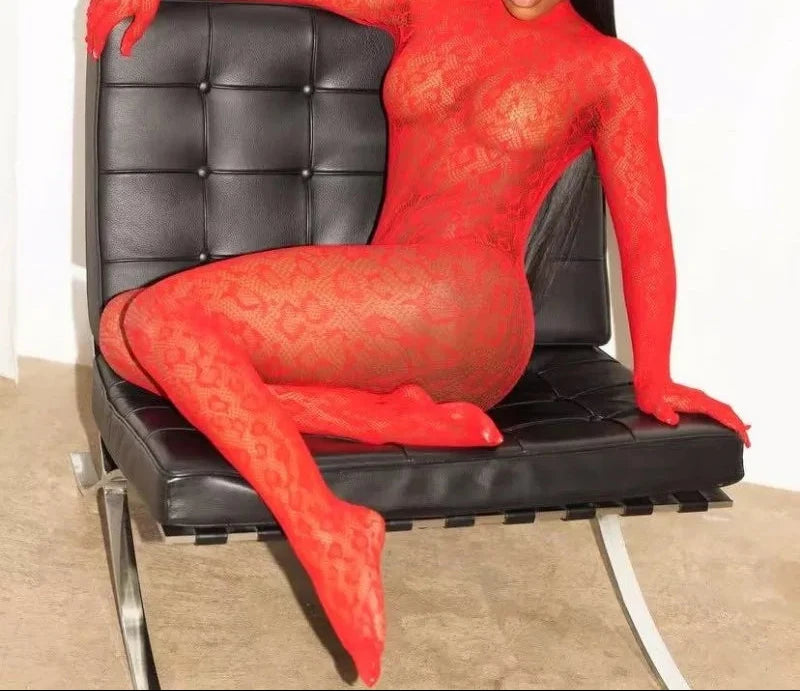 Person wearing a red lace bodysuit sitting on a black chair.