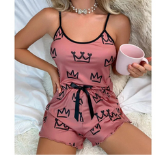 Woman wearing a pink pajama set with black crowns, holding a pink mug.