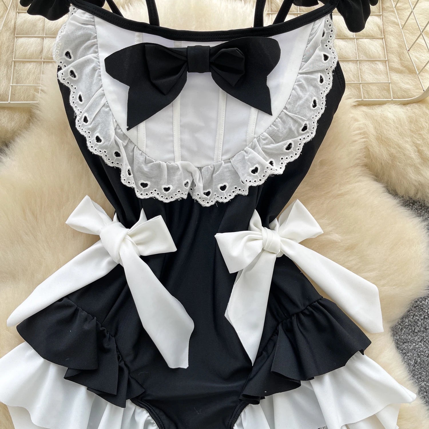 Black and white maid costume with ruffles and bows on a textured surface
