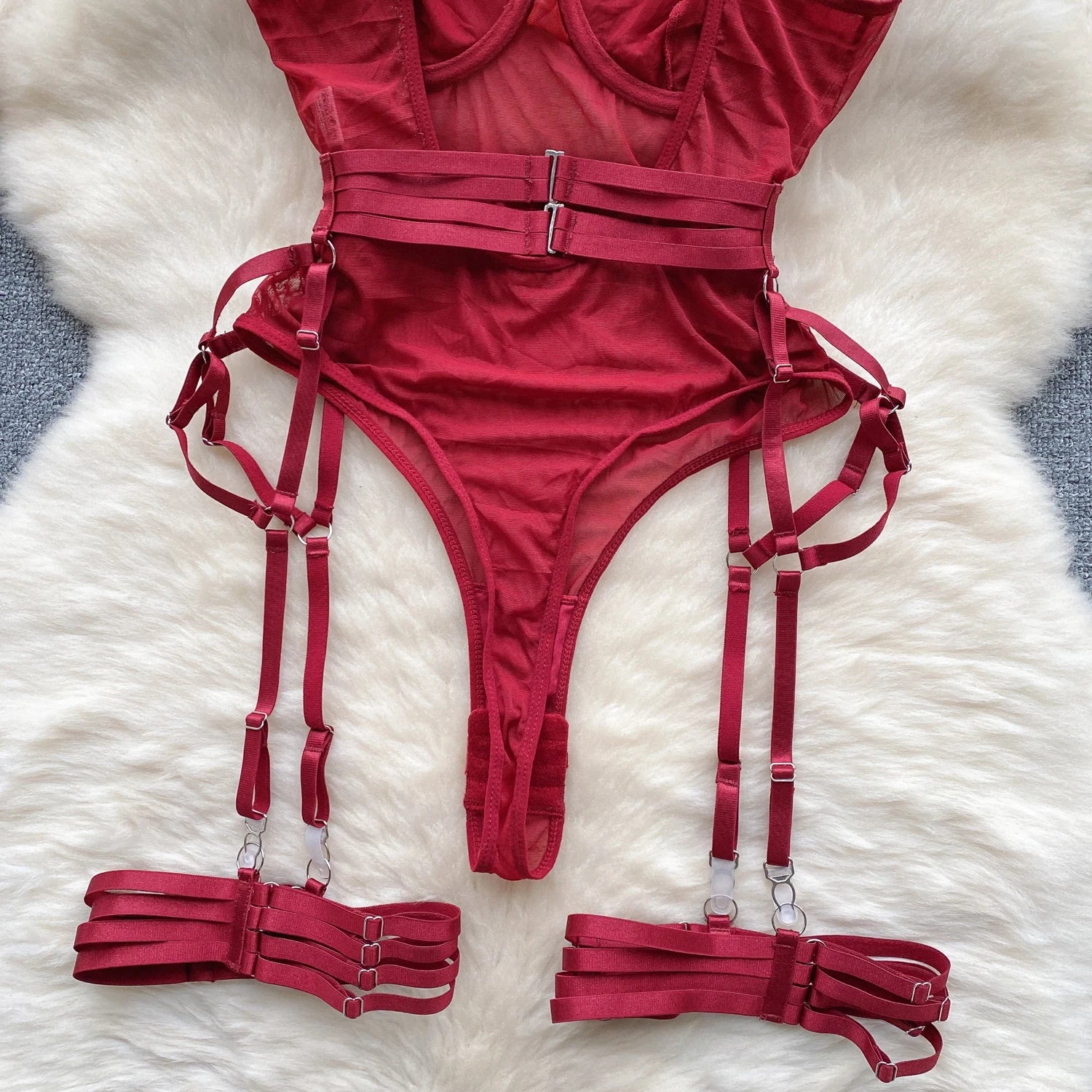 Red lingerie set with straps on a white fur surface