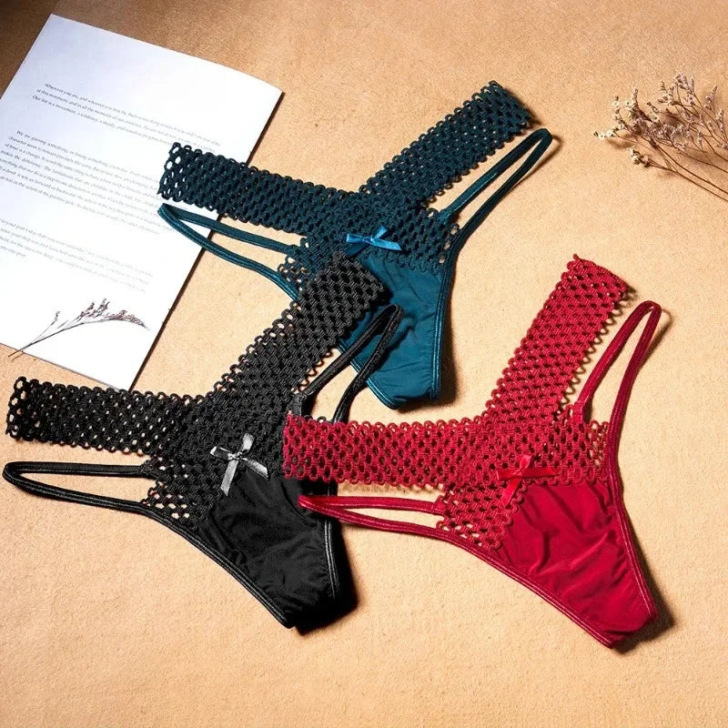 Three fishnet lingerie sets in black, blue, and red on a beige surface with a paper and flowers.