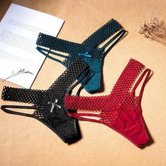 Three fishnet lingerie sets in black, blue, and red on a beige surface with a paper and flowers.