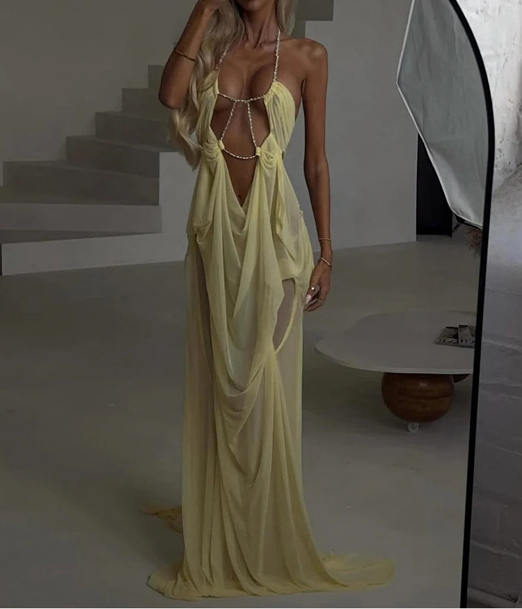Woman wearing a yellow evening gown with a high slit in a minimalistic setting.