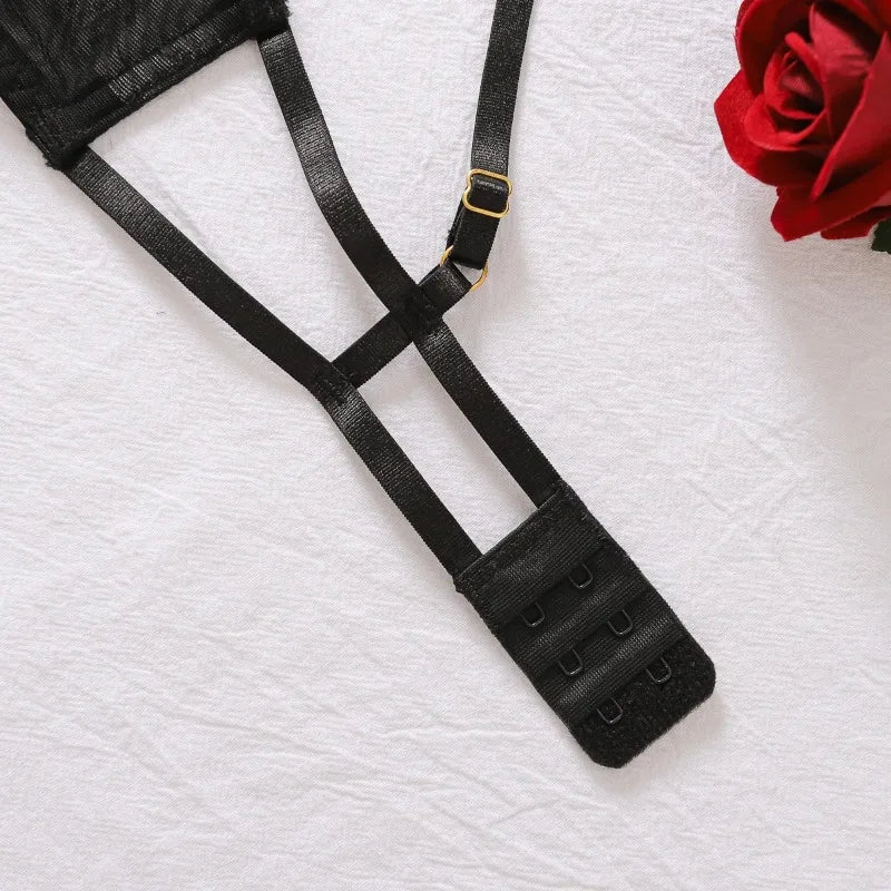 Black garter belt on a textured white surface with a red rose.