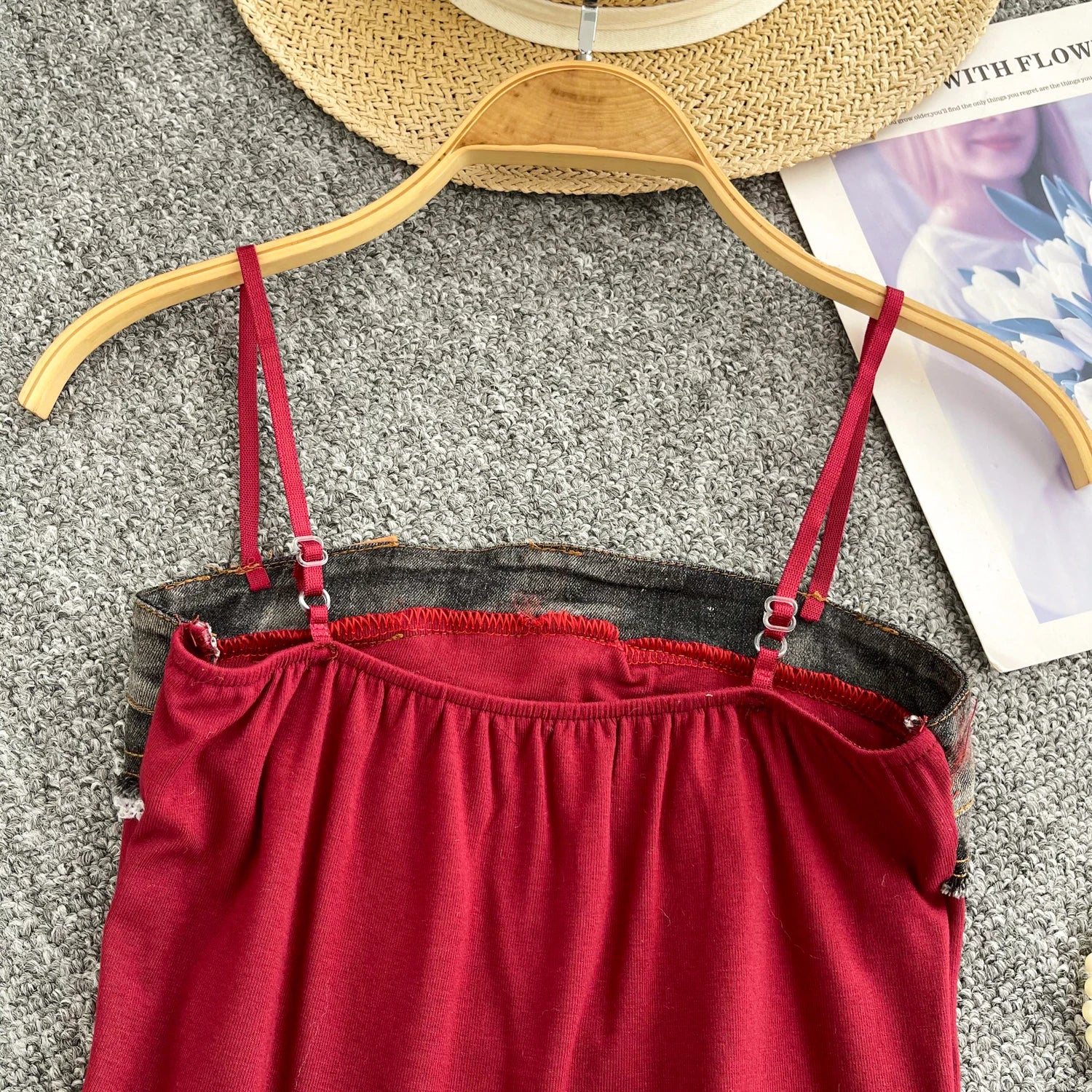 Red dress with red straps on a wooden hanger against a gray background