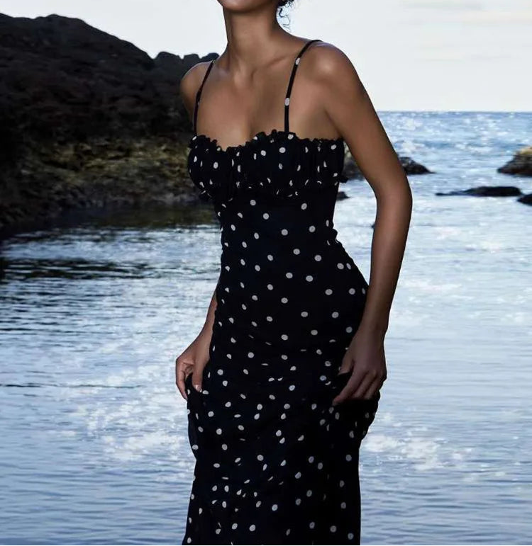 Woman in a black polka dot dress standing by a body of water with 'WeirdPuss' branding.