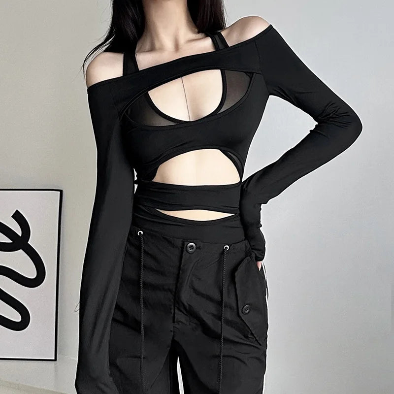 Person wearing a black outfit with cut-out design against a plain background