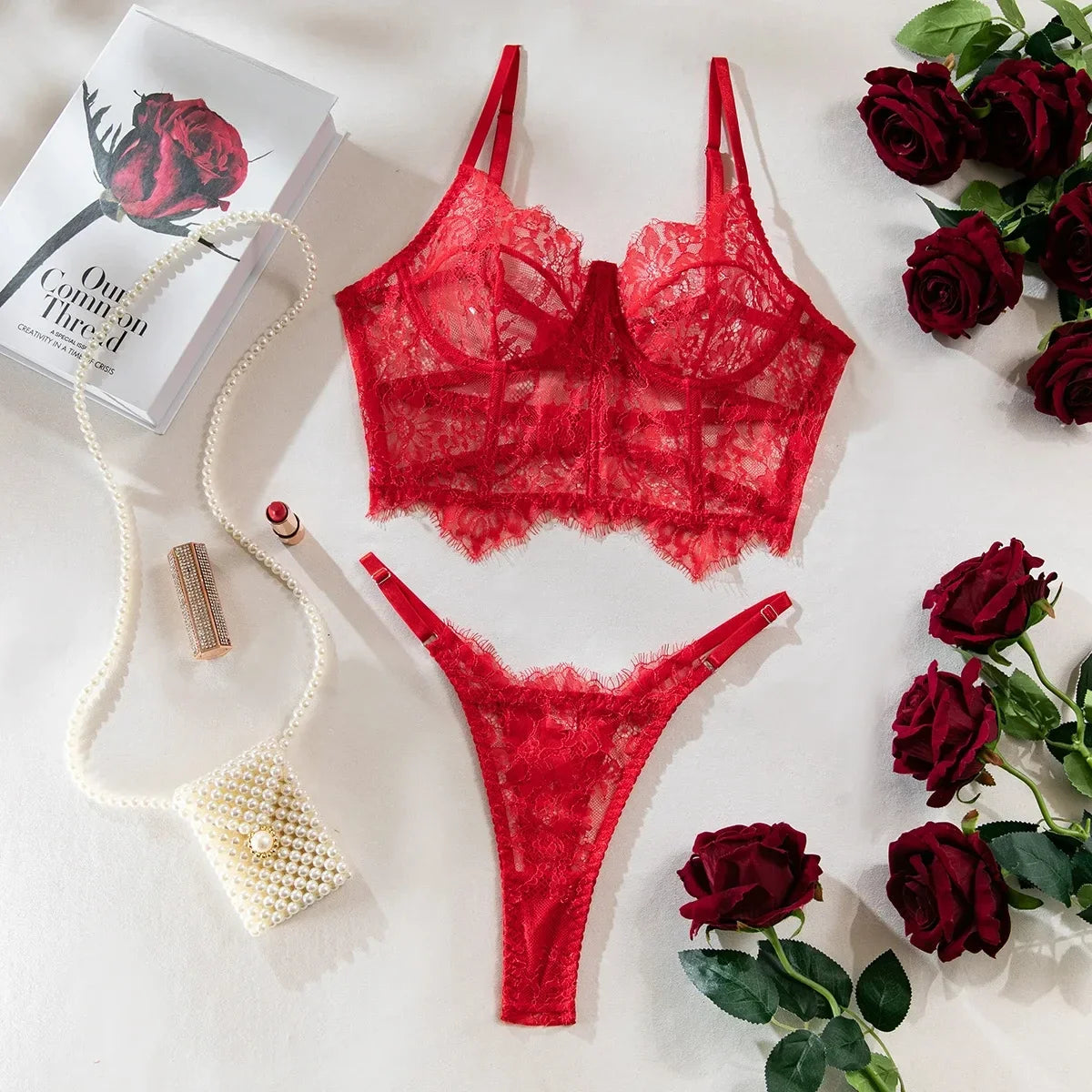 Red lace lingerie set with roses and a book on a white surface