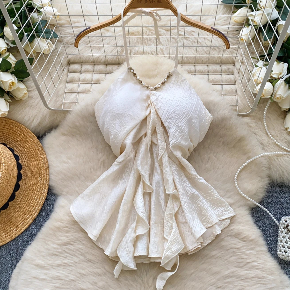 White lace dress on a hanger with decorative items on a fur surface