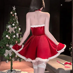 Person wearing a red dress with white trim in front of a decorated Christmas tree.