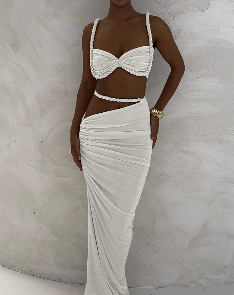 Woman wearing a white braided top and skirt against a textured white background