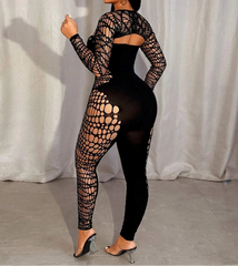 Woman wearing a black fishnet outfit against a white curtain background