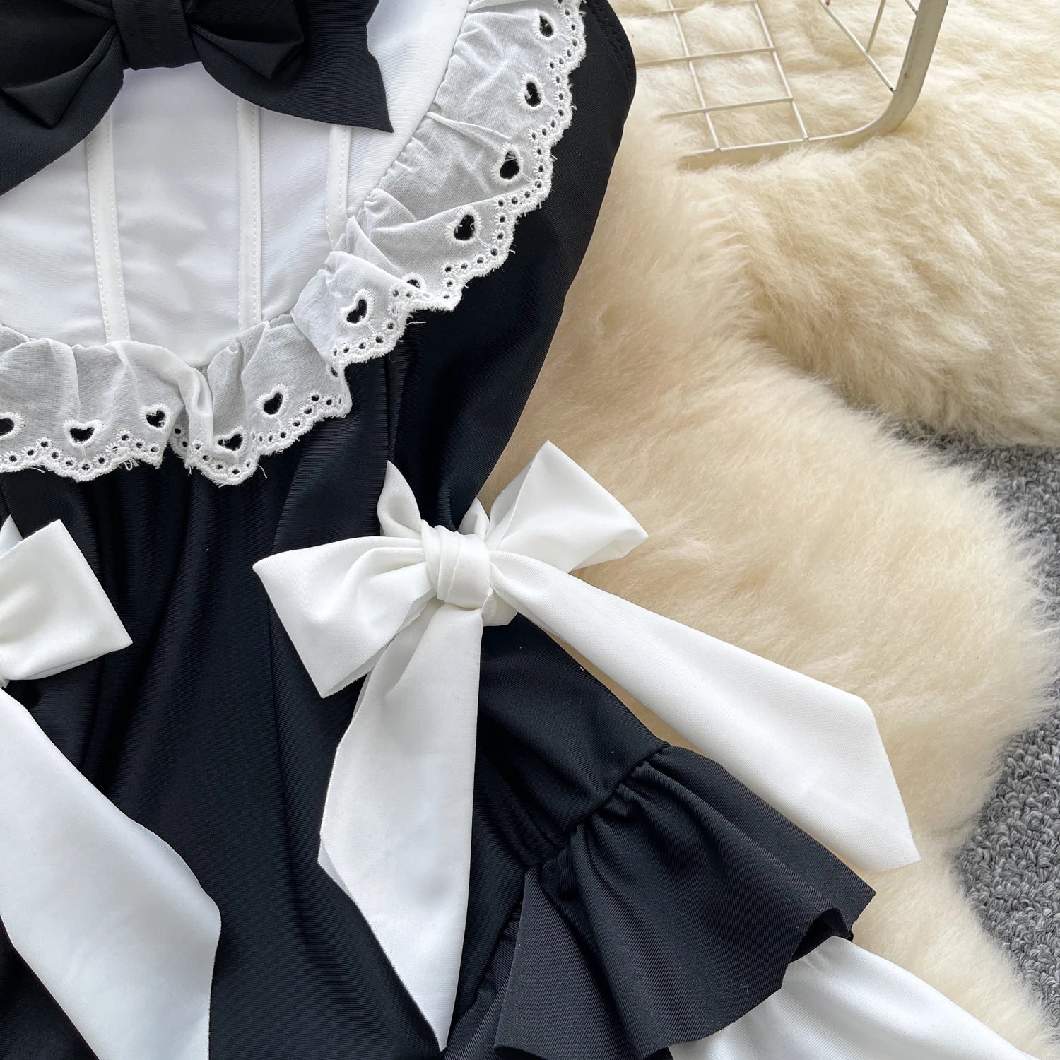 Black and white dress with lace details and bows on a textured surface