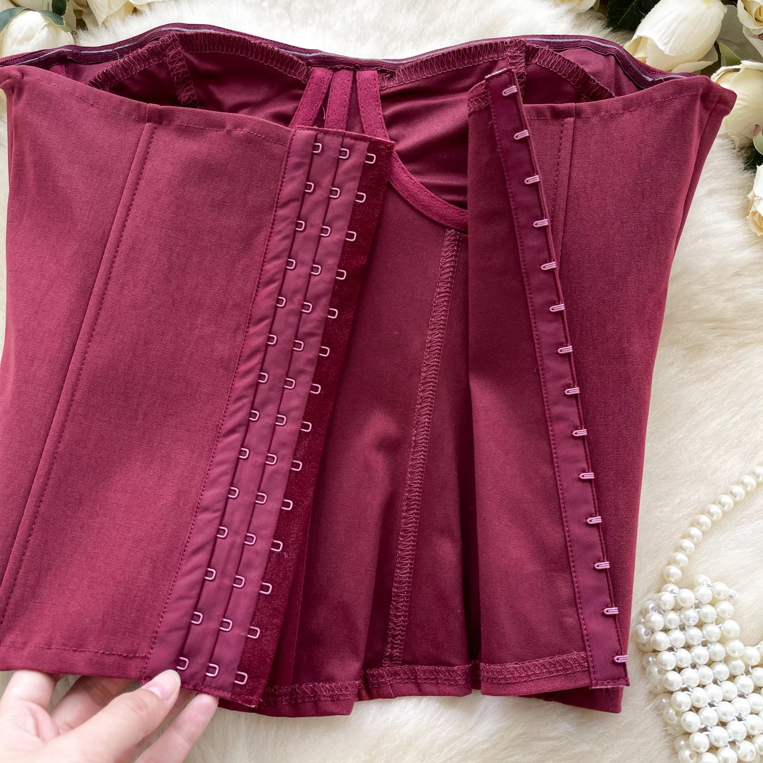 Maroon corset with lacing on a light background
