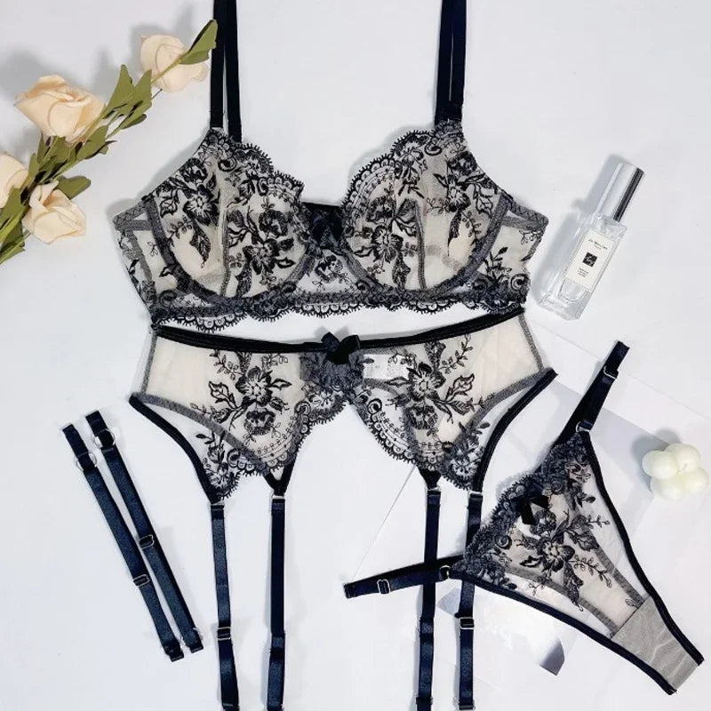 Black lace lingerie set with flowers and a bottle on a white background