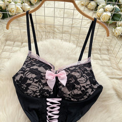 Black lace bra with pink bows on a hanger against a floral background