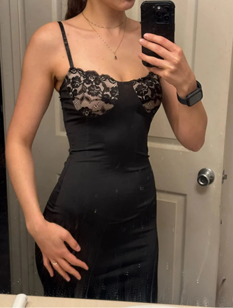 Person wearing a black dress with lace details, taking a mirror selfie.