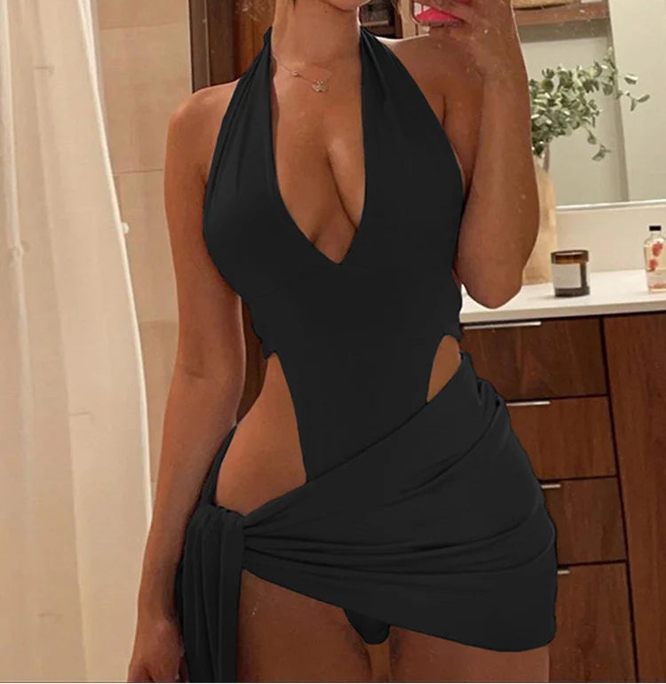 Woman taking a mirror selfie wearing a black halter neck dress with cut-out design.