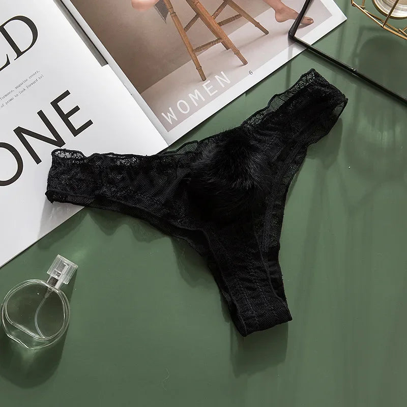 Black lace thong on a green surface with a magazine and perfume bottle.