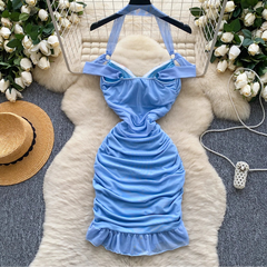 Blue halter dress on a hanger with decorative flowers and a hat in the background
