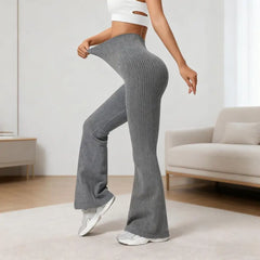 Person wearing gray ribbed flared pants in a room with a light-colored sofa and wooden floor.