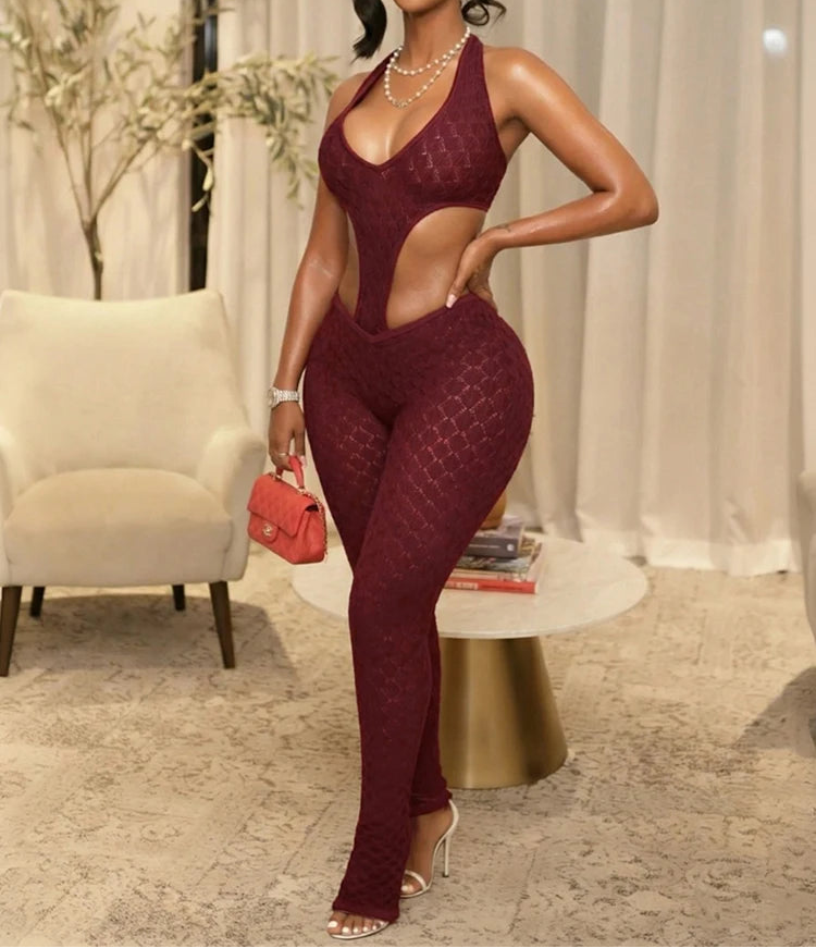 Woman in a burgundy jumpsuit posing in an elegant room.